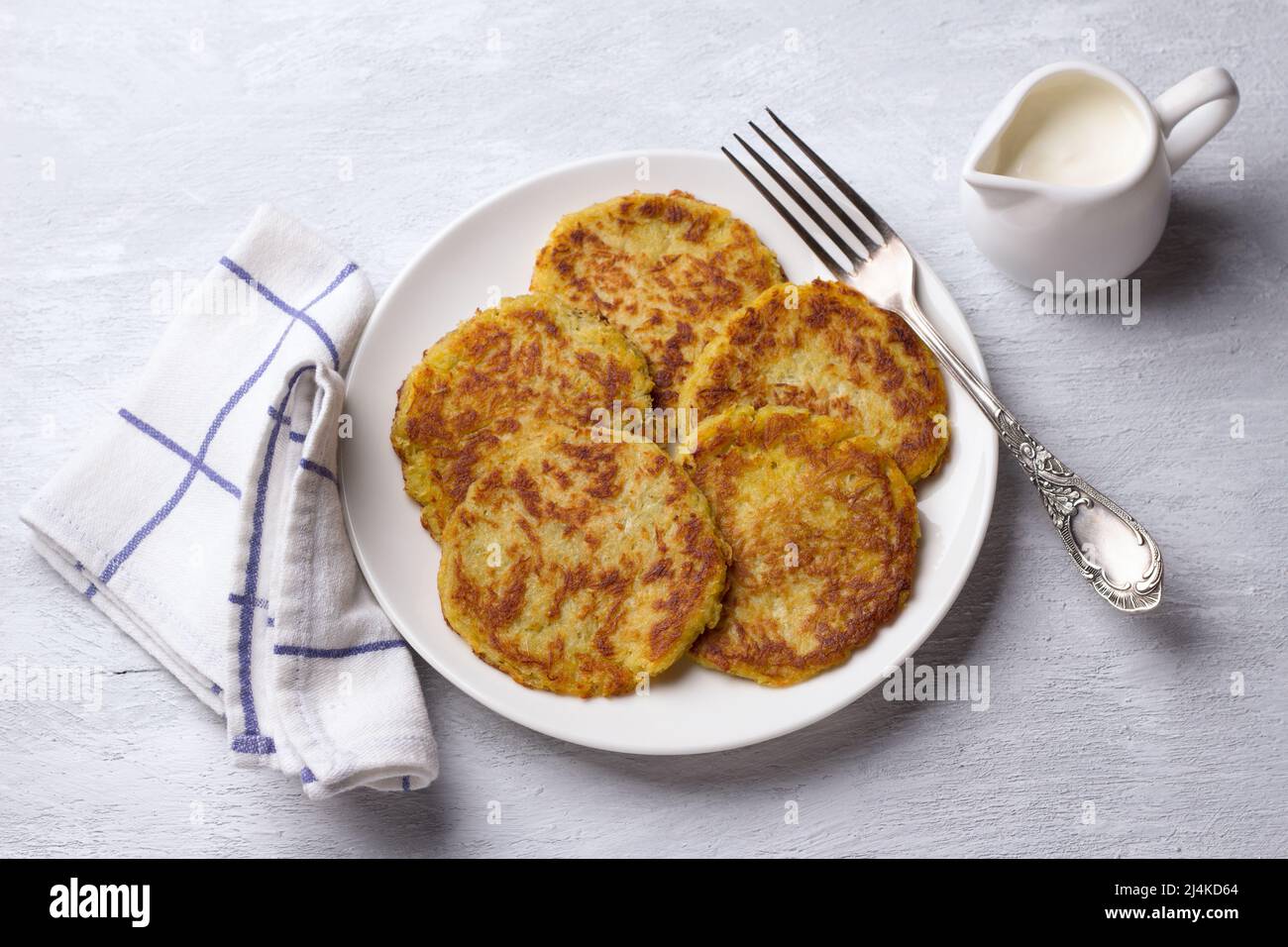 Traditionelle Latkes-Krabben mit saurer Creme auf hellgrauem texturiertem Hintergrund, Draufsicht Stockfoto