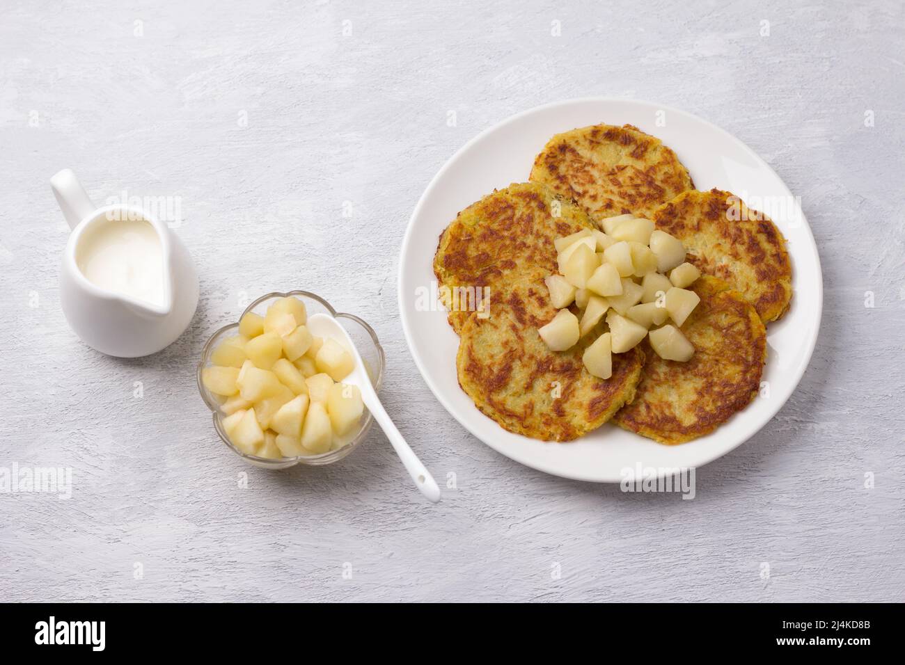 Traditionelle Latkes-Krapfen mit saurer Creme- und Apfelsauce auf hellgrauem texturiertem Hintergrund, Draufsicht Stockfoto