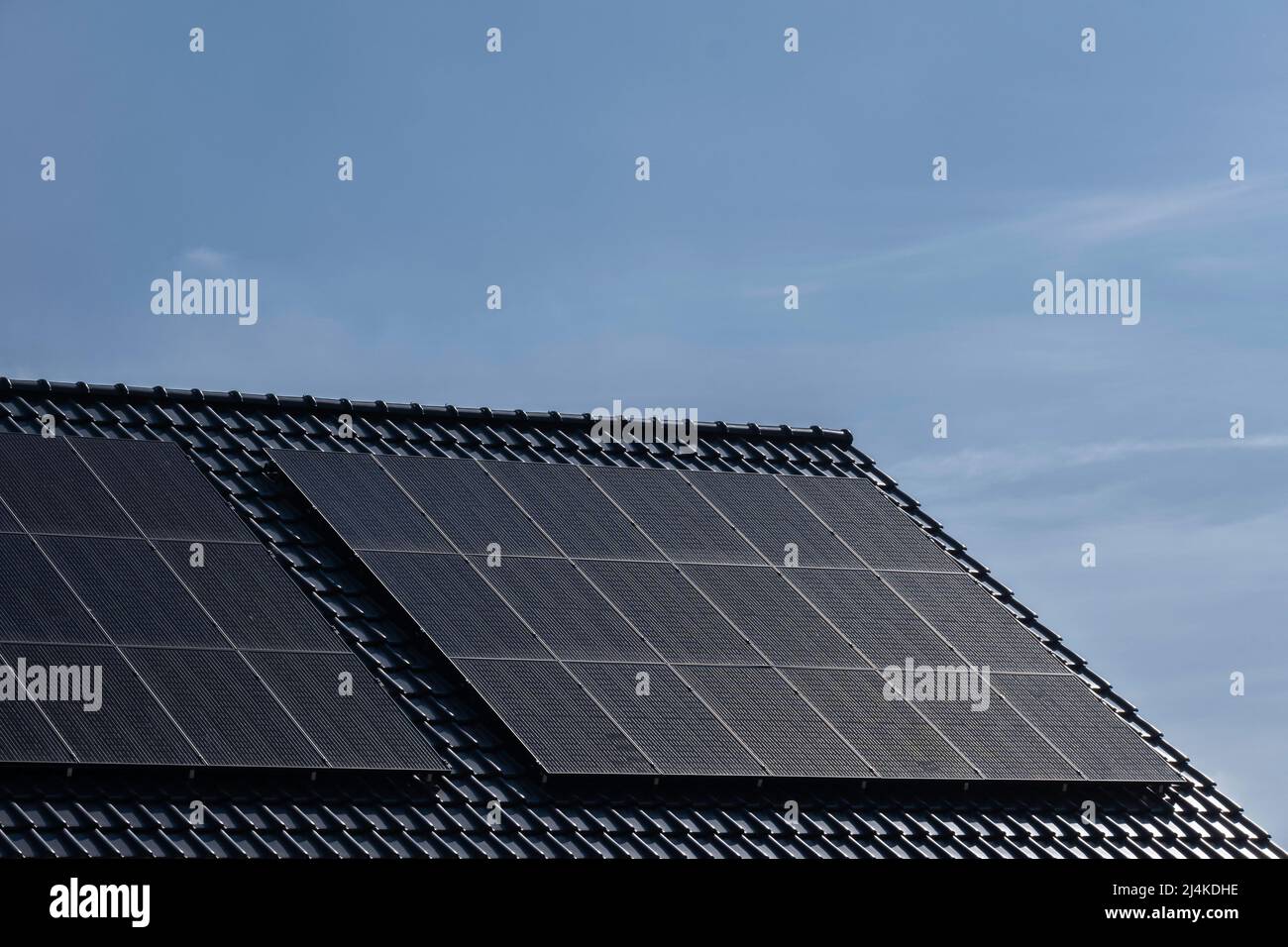 Solarmodule, die auf dem Ziegeldach eines modernen Neubaus in den Niederlanden mit blauem Himmel montiert sind. Nachhaltige Energie Stockfoto