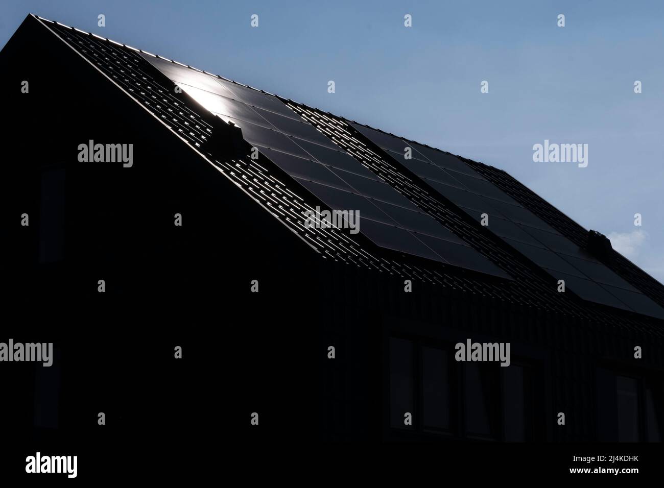 Sonnenkollektoren, die auf den Dächern eines modernen Neubaus in einer Straße in den Niederlanden mit Sonne und blauem Himmel montiert sind. Nachhaltige Energie Stockfoto