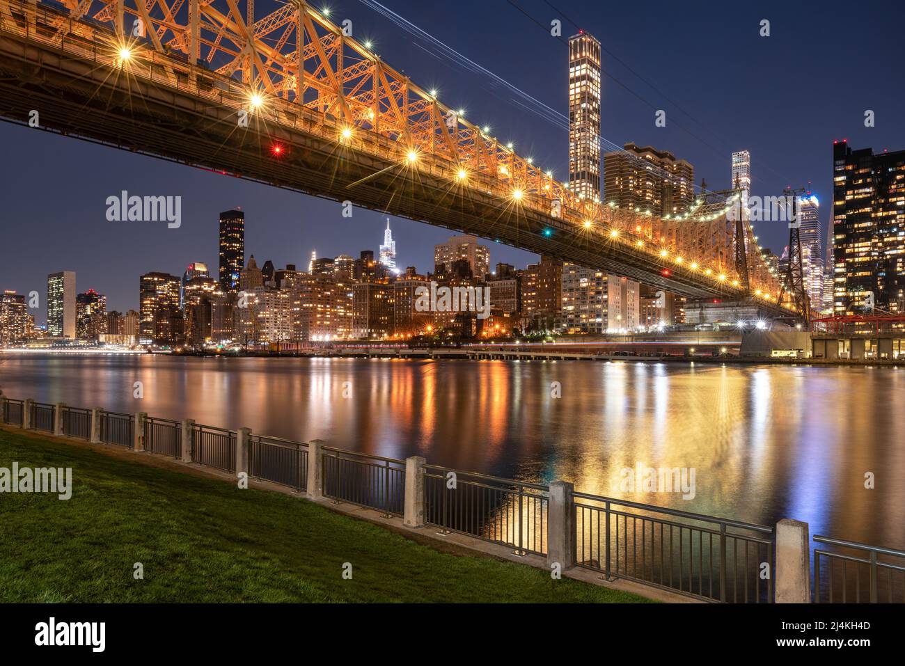 Beleuchtete Queensborough Bridge, die sich von der Upper East Side von Manhattan bis zur Roosevelt Island erstreckt. Abendansicht der Wolkenkratzer von New York City Stockfoto