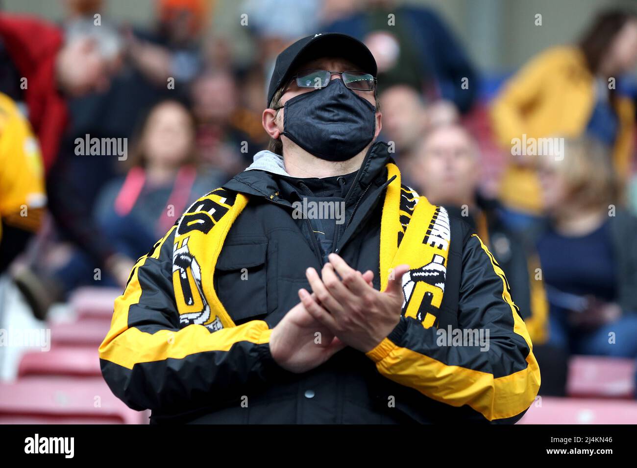 Ein Fan von Cambridge United applaudiert seinen Spielern, während er während des Sky Bet League One-Spiels im DW Stadium, Wigan, eine Gesichtsmaske trägt. Bilddatum: Samstag, 16. April 2022. Stockfoto