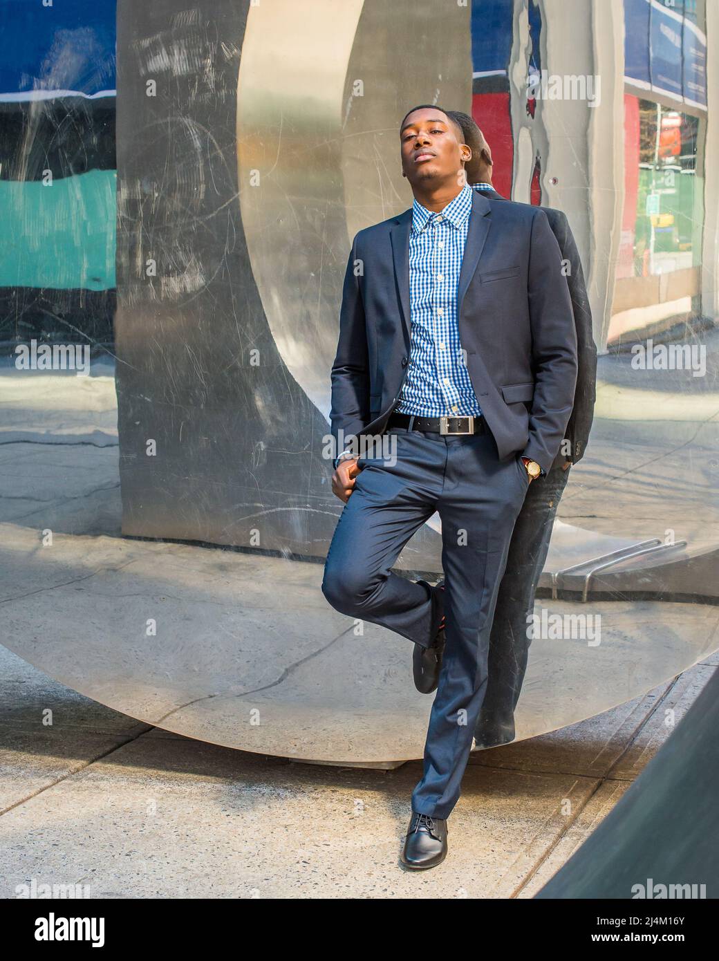 Tränen in den Augen lehnt sich ein junger schwarzer Geschäftsmann an eine moderne Spiegelwand, die emotional zerbrochen ist. Stockfoto