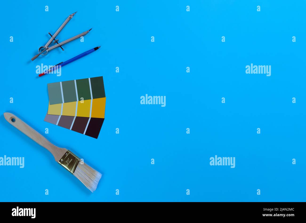 Blauer Schreibtisch mit Designer-Werkzeugen für Architekten, bestehend aus mechanischem Bleistift, Farbmusterkarten, Pinsel und Kompass. Stockfoto
