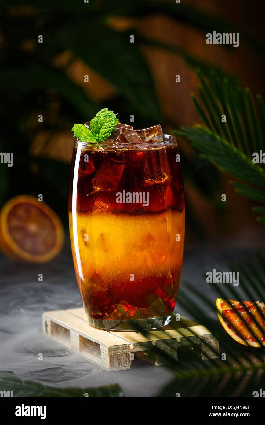 Bumble Kaffee mit Eis auf einem dunklen tropischen Hintergrund. Espresso, Orangensaft und Sirup in Schichten Stockfoto