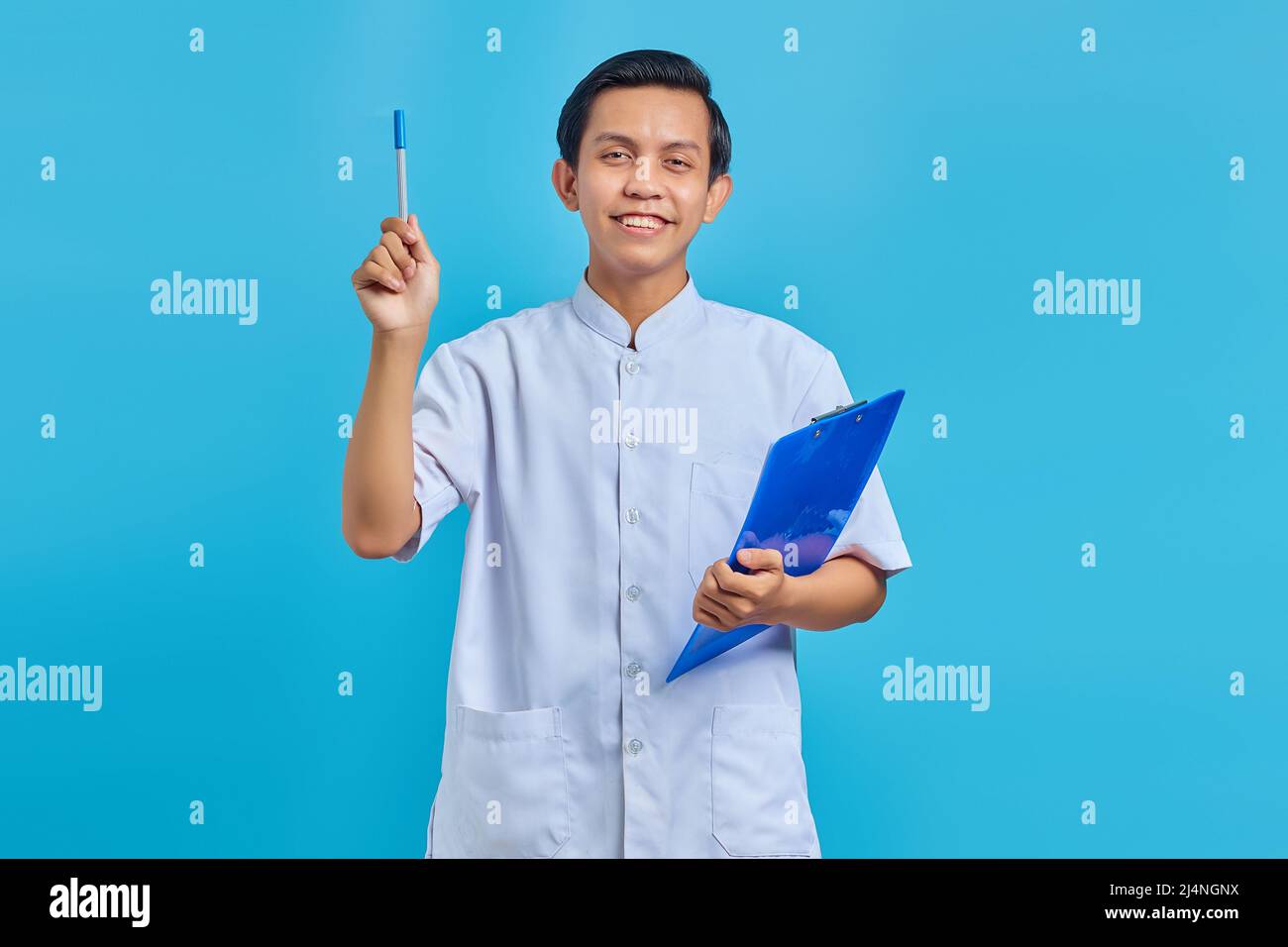 Attraktive junge asiatische männliche Krankenschwester hält Stift und mit guten Idee isoliert über blauen Hintergrund Stockfoto