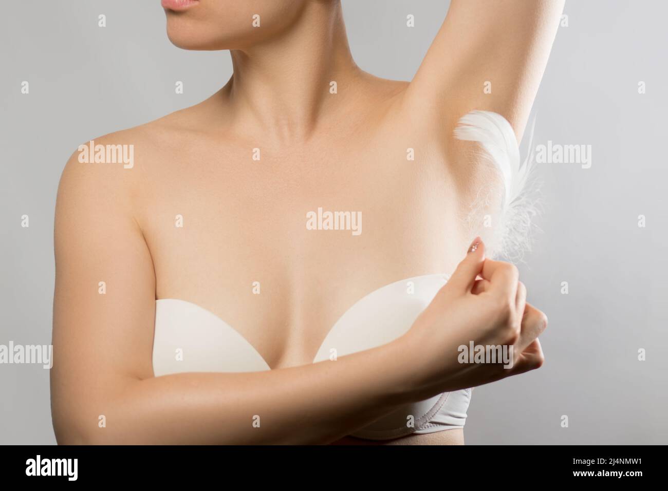 Achselepilation, Haarentfernung. Junge Frau hält ihre Arme hoch und zeigt saubere Achselhöhlen, Enthaarung glatte klare Haut . Schönheitsporträt. Weiße Fea Stockfoto