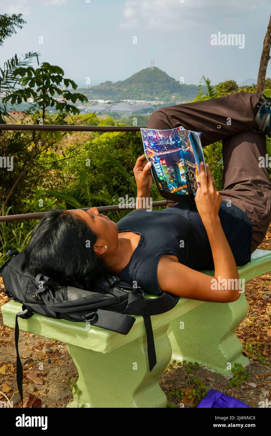 Eine weibliche Touristin liest ein Magazin auf einer Bank im Metropolitan Park, Panama City, Provinz Panama, Republik Panama, Mittelamerika. Stockfoto
