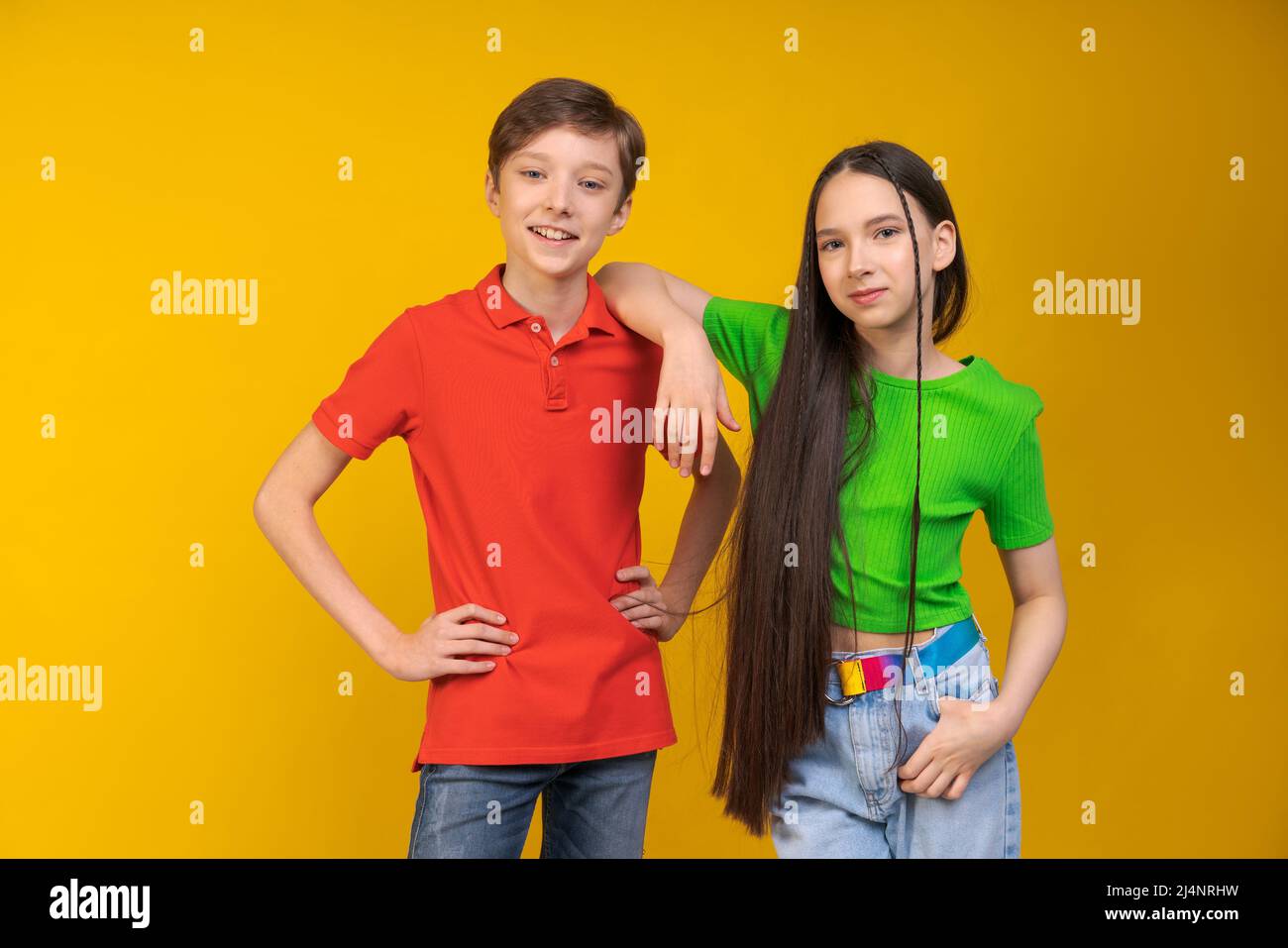 Kerl und Mädchen in hellen T-Shirts auf gelbem Hintergrund Mädchen legte ihre Hand auf die Schulter des Mannes. Nette Teenager schauen auf die Kamera. Jugendfreundschafts- und Unterstützungskonzept Stockfoto