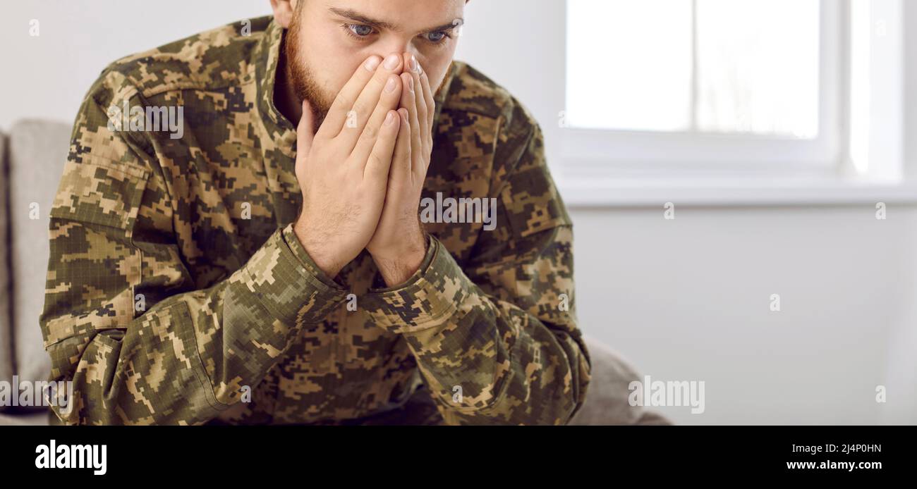 Junger depressiver Militärveteran, der PTSD auf dem Sofa sitzen und an Krieg denken muss Stockfoto