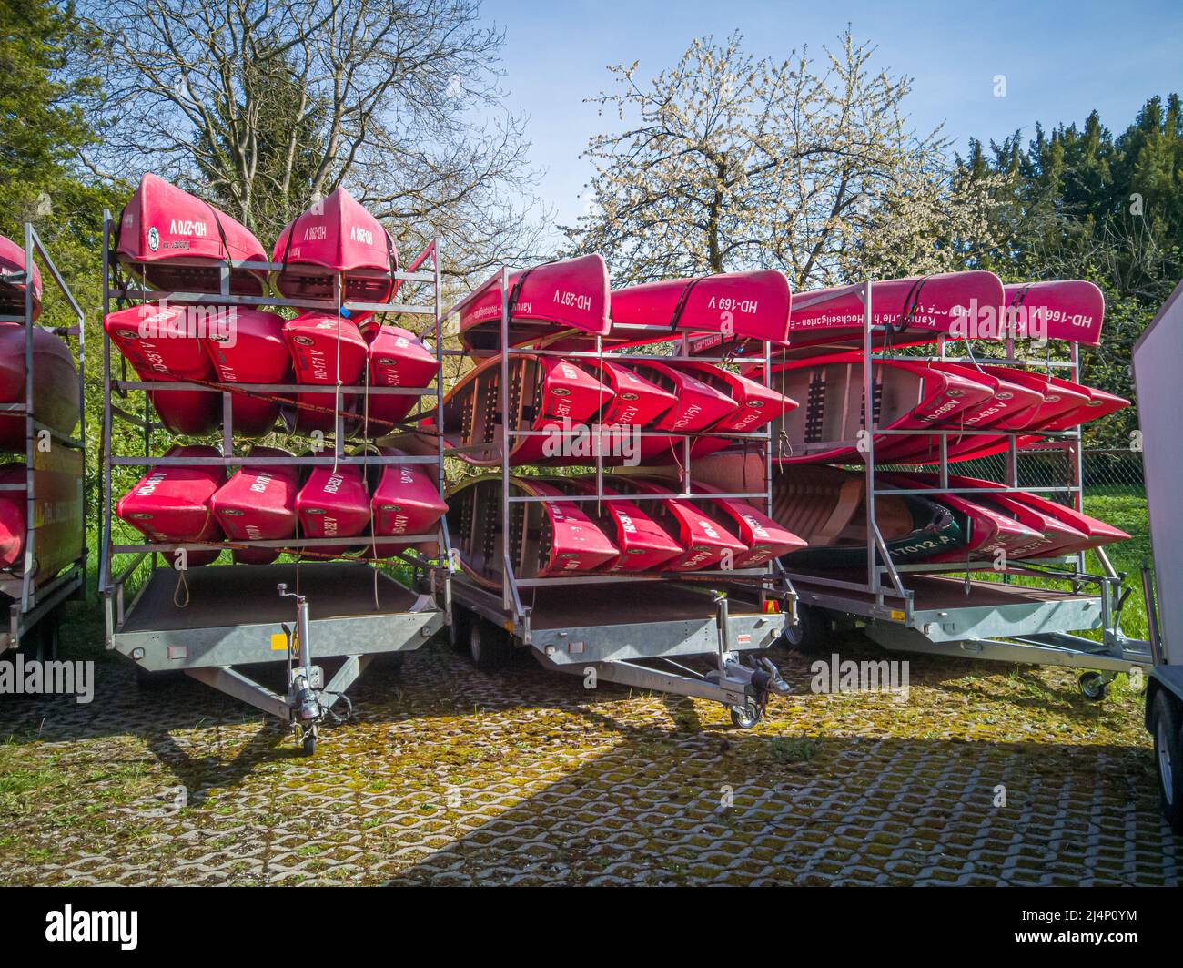 Neckargemuend, Deutschland: 11. April 2022: Rote Kanus auf einem Anhänger im Frühjahr warten darauf, im Sommer für touristische Flußtouren eingesetzt zu werden Stockfoto