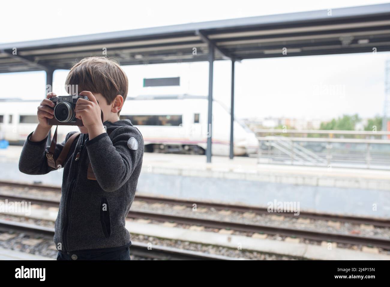 Kleiner Junge, der am Bahnhof fotografiert. Reisen im Zug mit Kindern Konzept Stockfoto