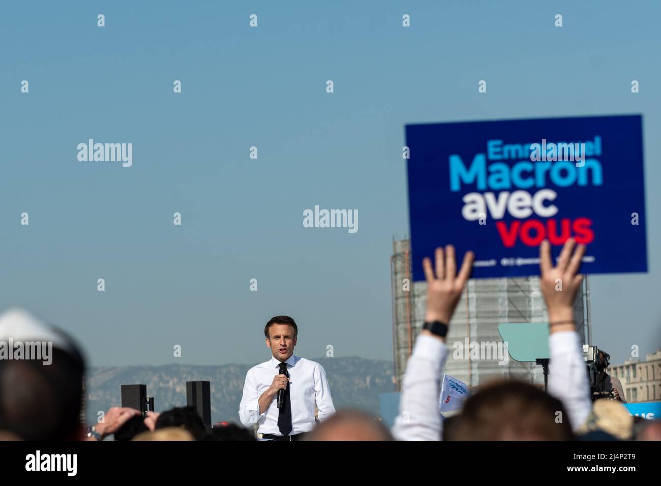 Emmanuel Macron sieht auf der Bühne Reden halten und ein Unterstützer hält ein Plakat mit den Slogans der Kampagne "avec vous (with you)" hoch. Emmanuel Macron ist in Marseille zu einem Treffen der zweiten Runde der Präsidentschaftswahlen, das ihn am 24. April 2022 gegen Marine Le Pen stellt. Er muss die Stimme der Wähler anziehen, die sich für Jean-Luc Mélenchon entschieden haben (radikale ökologische Sensibilität der Linken). Er kündigte starke Auswirkungen seiner künftigen Politik im Hinblick auf den Umweltschutz und die Bedeutung der Jugend für die Entscheidungen an, die getroffen werden, wenn er erneut gewählt wird. Er rief auch an, um zu schlagen Stockfoto