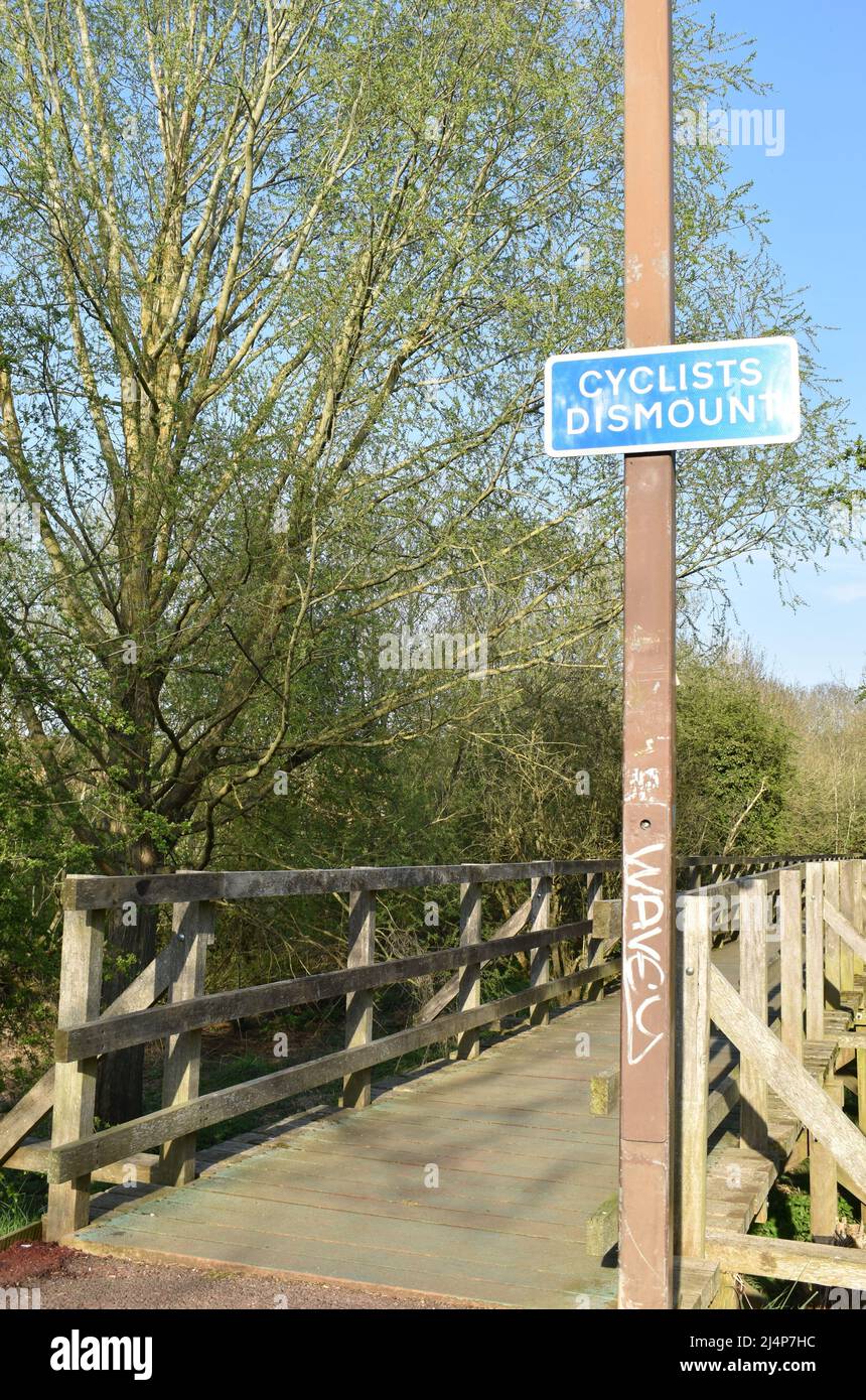 Schild „Radler demontieren“ auf einer Holzbrücke mit Copyspace. Stockfoto