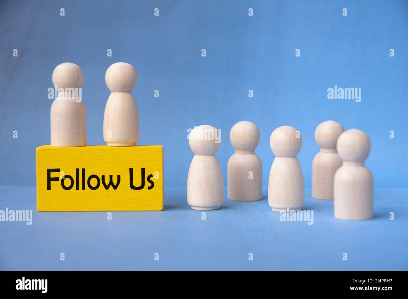 Folgen Sie uns Text auf gelbem Holzblock, umgeben von Holzpuppen. Stockfoto