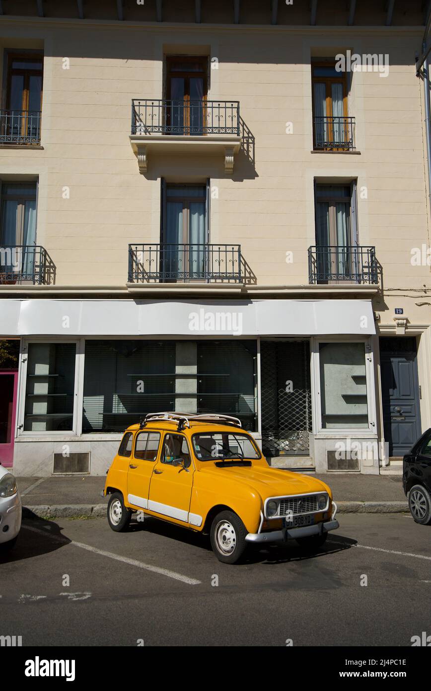 Yellow Orange Renault 4 GTL - Klassisches französisches Auto, das vor einem Geschäft in einer französischen Stadt geparkt ist. Stockfoto