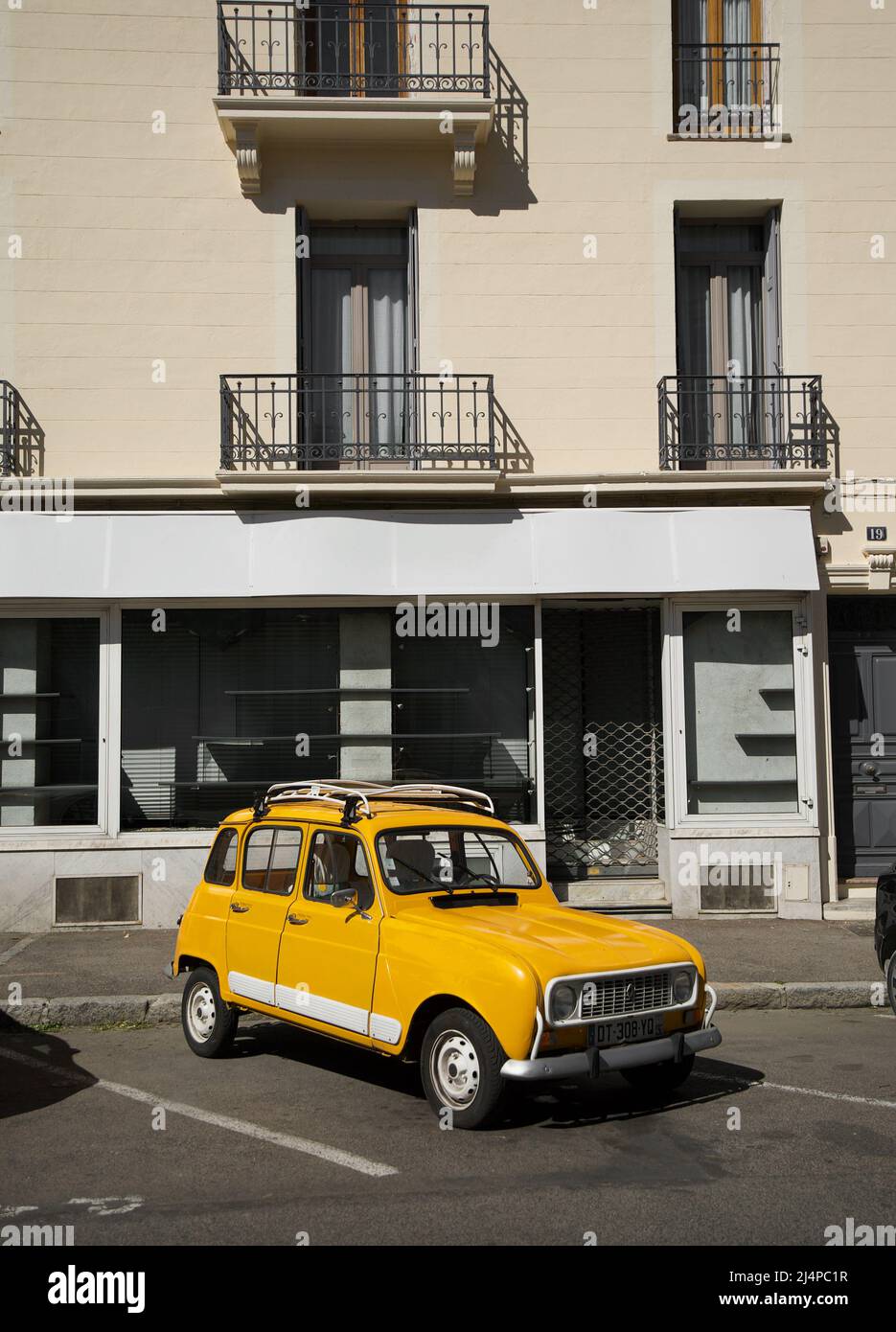 Yellow Orange Renault 4 GTL - Klassisches französisches Auto, das vor einem Geschäft in einer französischen Stadt geparkt ist. Stockfoto