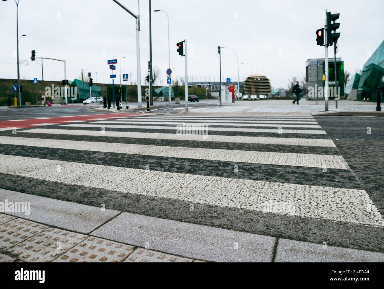 Fußgängerübergang, der durch eine Ampel gesteuert wird. Roter Fahrradteppich mit weißen Streifen. Stockfoto