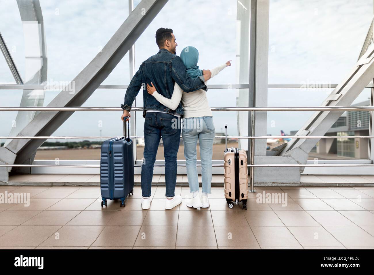 Wochenendausflug. Islamisches Paar, Das In Der Nähe Von Window Im Flughafen Stand Und Wegzeigte Stockfoto