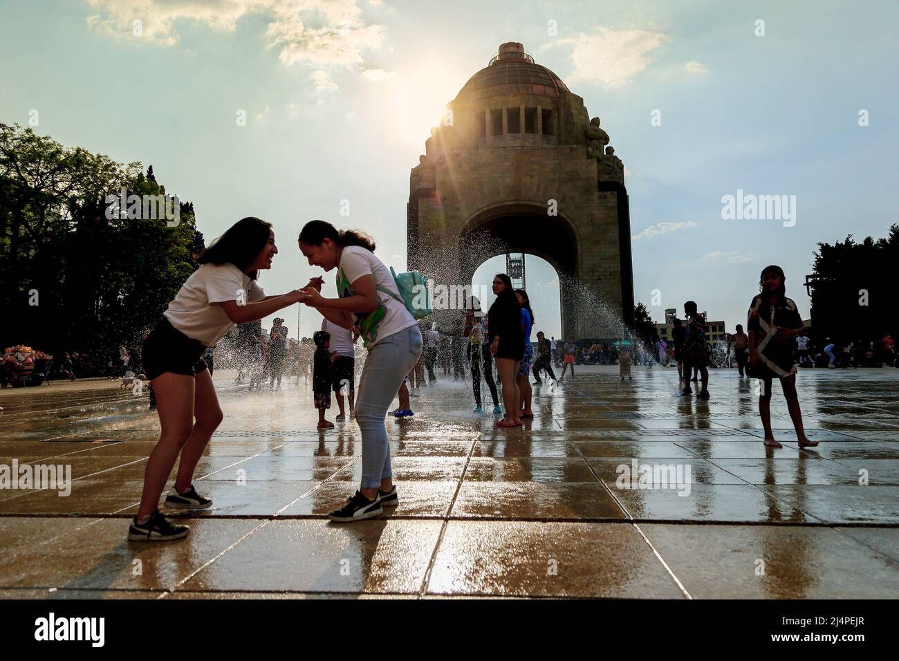 Mexiko, Mexiko. 16. April 2022. Familien spielen mit Wasser in den Brunnen des Revolutionsdenkmals während der Feierlichkeiten der Karwoche. In Mexiko wurde viele Jahre lang der Glaube aufrechterhalten, dass die Menschen an diesem Tag mit Eimern voller Wasser übergossen wurden, sobald sie ihre Häuser verlassen hatten. Jetzt wird die Wasserverschwendung in Mexiko mit Bußgeldern und sogar Festnahmen von bis zu 24 Stunden wegen Wassermangel im Land bestraft, der stärker als zuvor vorhanden ist, also kommen Leute stattdessen hierher zum Revolutionsdenkmal, um mit dem Brunnenwasser zu spielen. Kredit: SOPA Images Limited/Alamy Live Nachrichten Stockfoto