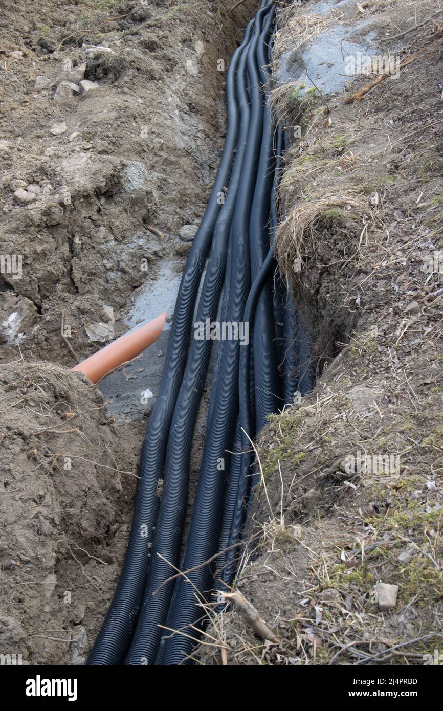 Schwarze Drainagerohre aus Wellkunststoff, die in einem Graben auf einer Baustelle verlegt werden Stockfoto