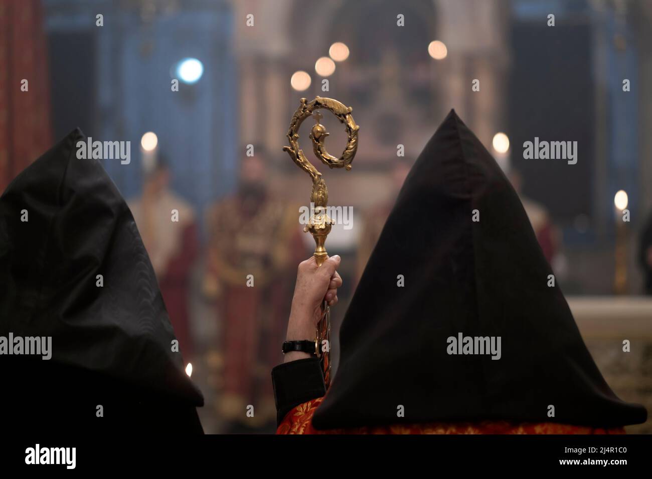 Ein Mitglied der armenisch-apostolischen Kirche in seinem schwarzen Kapuzenbeet hält einen im östlichen Stil gehaltenen Bischofsstab mit Schlange, der den Stab Moses während eines religiösen Gottesdienstes in der Grabeskirche in der Altstadt von Jerusalem Israel darstellt Stockfoto