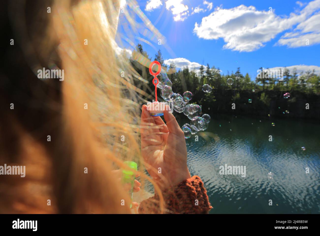 Mädchen bläst Seifenblasen in der Natur in der Nähe des Sees Stockfoto