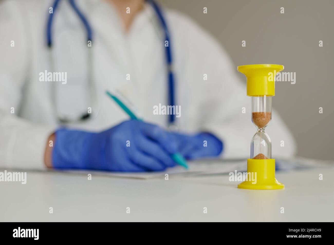 Sanduhr mit der Zeit knapp und Arzt im Laborkittel Notizen oder Rezept im Journal. Stockfoto