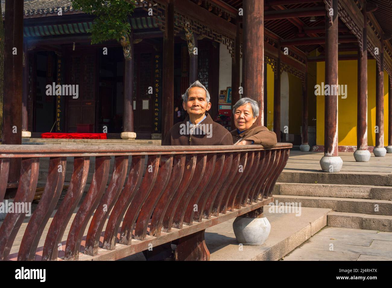 ANQING, CHINA - 22. MÄRZ: Ältere Männer und Frauen sitzen auf einer langen Bank, um eine Pause zu machen. Ein älteres Paar, 80 Jahre alt, sitzt auf einer Bank im Yinjiang TEM Stockfoto