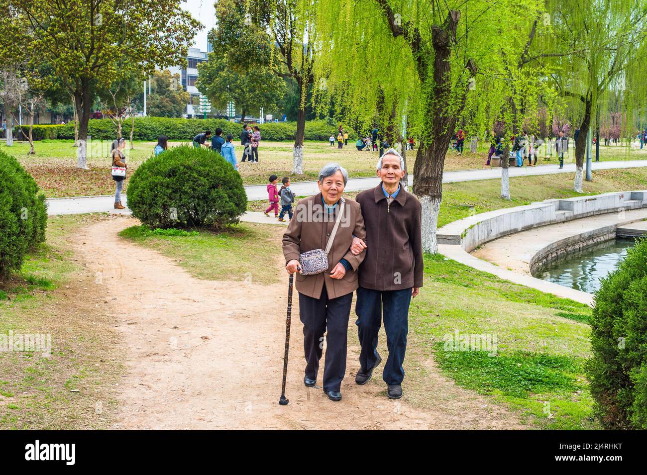 Ältere Männer und Frauen, die nach draußen gehen. Ein älteres Paar, 80 Jahre alt, sich gegenseitig hilfend, Arm in Arm, läuft auf einem Park, Frau hält einen Spaziergang Stockfoto