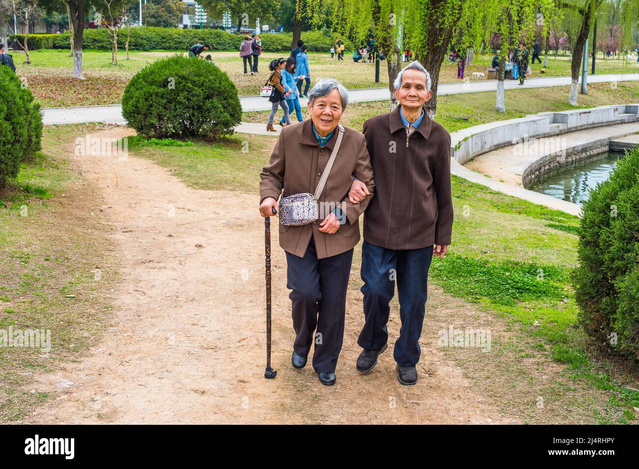 Ältere Männer und Frauen, die nach draußen gehen. Ein älteres Paar, 80 Jahre alt, sich gegenseitig hilfend, Arm in Arm, läuft auf einem Park, Frau hält einen Spaziergang Stockfoto