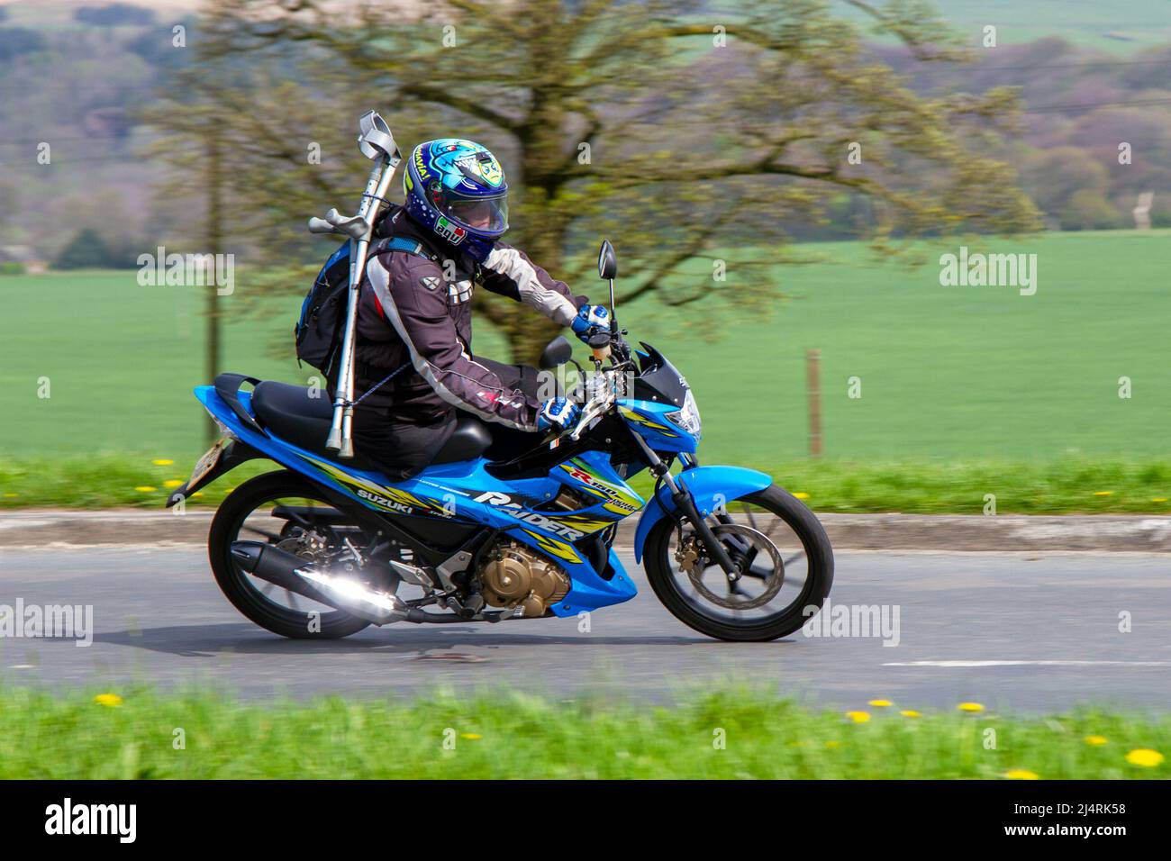 Behinderter, amputierter Fahrer auf dem 2013 Suzuki Blue Motorrad 149cc, mit zwei Krücken, in Manchester, Großbritannien Stockfoto