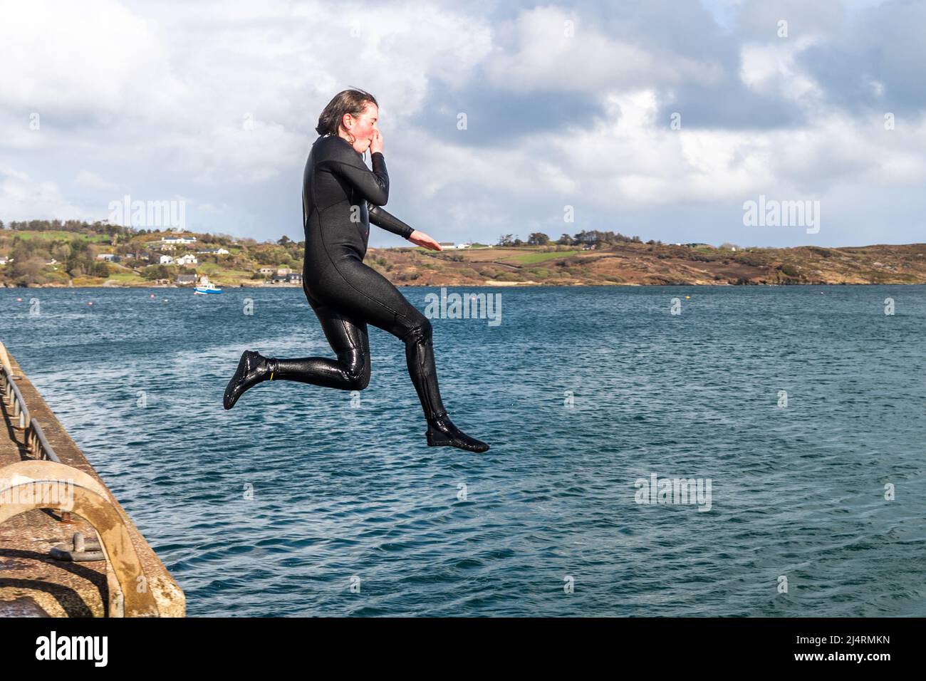 Schull, West Cork, Irland. 17. April 2022. An einem sonnigen, aber luftigen Tag in West Cork springt Ella Britton von Cobh vom Pier in Schull. Quelle: AG News/Alamy Live News Stockfoto