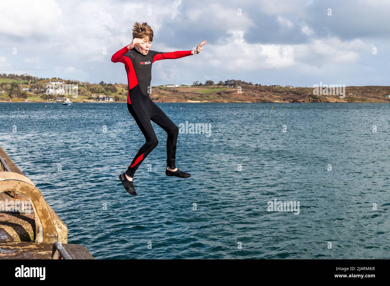 Schull, West Cork, Irland. 17. April 2022. An einem sonnigen, aber luftigen Tag in West Cork springt Alex Mansworth von Cobh vom Pier in Schull. Quelle: AG News/Alamy Live News Stockfoto