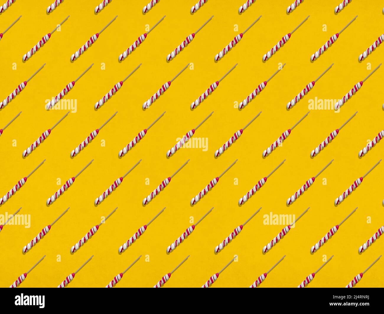 Viele süße Lutscher, die in Reihen auf gelbem Hintergrund angeordnet sind Stockfoto