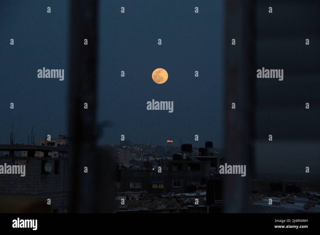 Mitten im Ramadan erhebt sich der „rosafarbene Mond“ über Gaza City. Dieses astronomische Phänomen kann im Vollmond während des Monats April von der Dämmerung bis zum Morgengrauen beobachtet werden. Gaza. Stockfoto