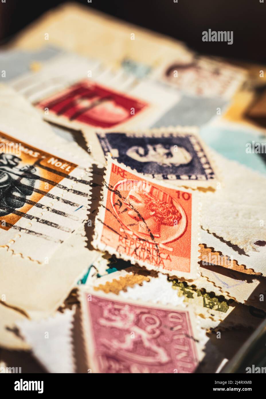 Ein vertikales Bild einer Sammlung alter Briefmarken mit Schwerpunkt auf einer orangefarbenen italienischen Briefmarke Stockfoto