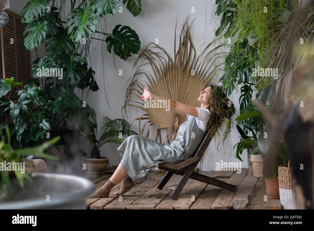 Zufriedene ruhige Frau Floristin Entspannung im Innengarten Genießen Sie geistige Balance und Wohlbefinden zu Hause Stockfoto