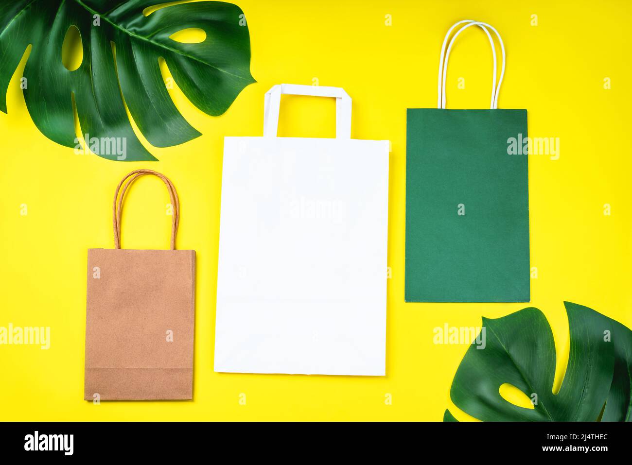 Umweltfreundliche Papiertüten auf gelbem Hintergrund. Einkaufstasche aus recyceltem Papier mit grünen Blättern auf gelbem Hintergrund. Zero Waste, plastikfreies Konzept Stockfoto