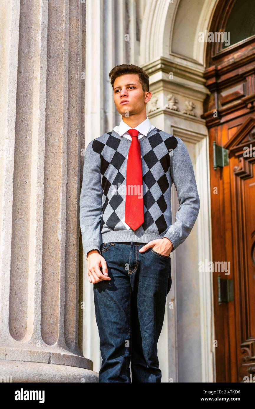 American College Student, der in New York studiert. Tragen Sie schwarzen,  weißen, grau gemusterten Pullover, rote Krawatte, Jeans, Ein junger Mann,  der außerhalb von Vintage steht Stockfotografie - Alamy
