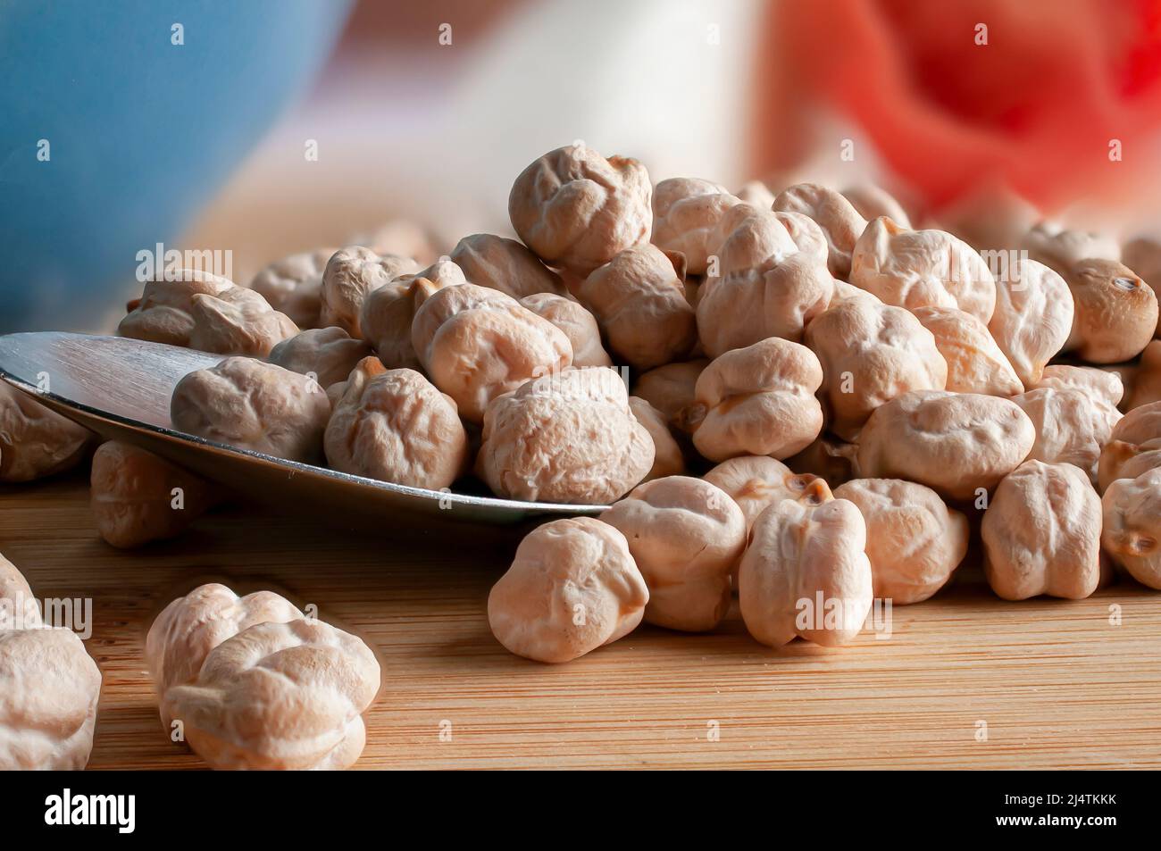 Makrofotografie, rohe oder ungekochte Kichererbsen auf einem Löffel mit blauer Zwiebel und Tomate auf dem Hintergrund Stockfoto
