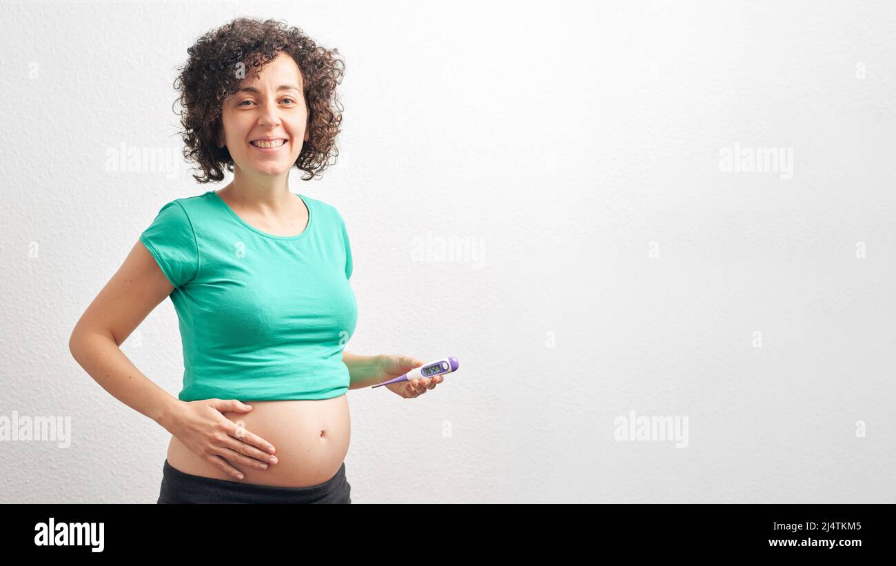 Schwangere mit Basalthermometer vor weißem Hintergrund Stockfoto