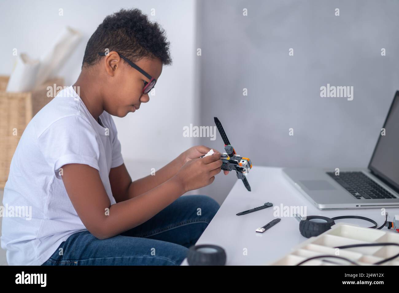 Ein dunkelhäutig gebauter Junge, der einen Transformator baut und beschäftigt aussieht Stockfoto