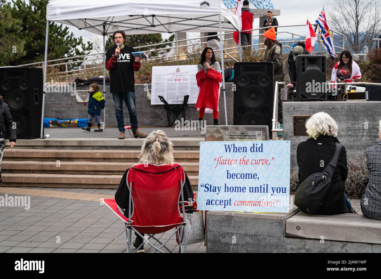 Foto von Zuschauern und ein Schild, das COVID mit dem Kommunismus bei einer Veranstaltung verbindet, um gegen die Impfvorschriften des Landes und andere COVID-Beschränkungen zu protestieren. Stockfoto