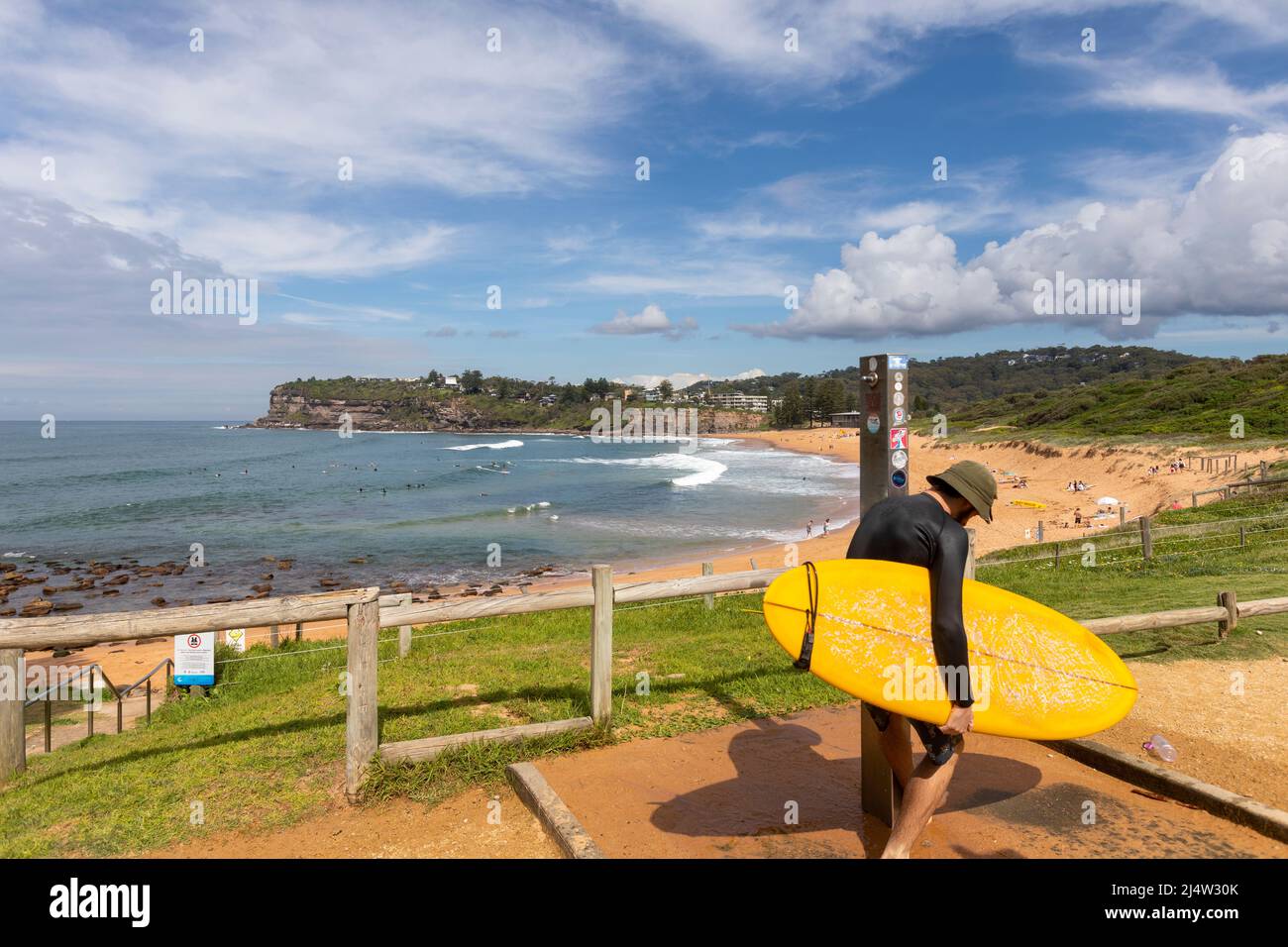 Surfer am Avalon Beach in Sydney beim Waschen des Surfbretts unter der Stranddusche, Sydney, NSW, Australien Stockfoto