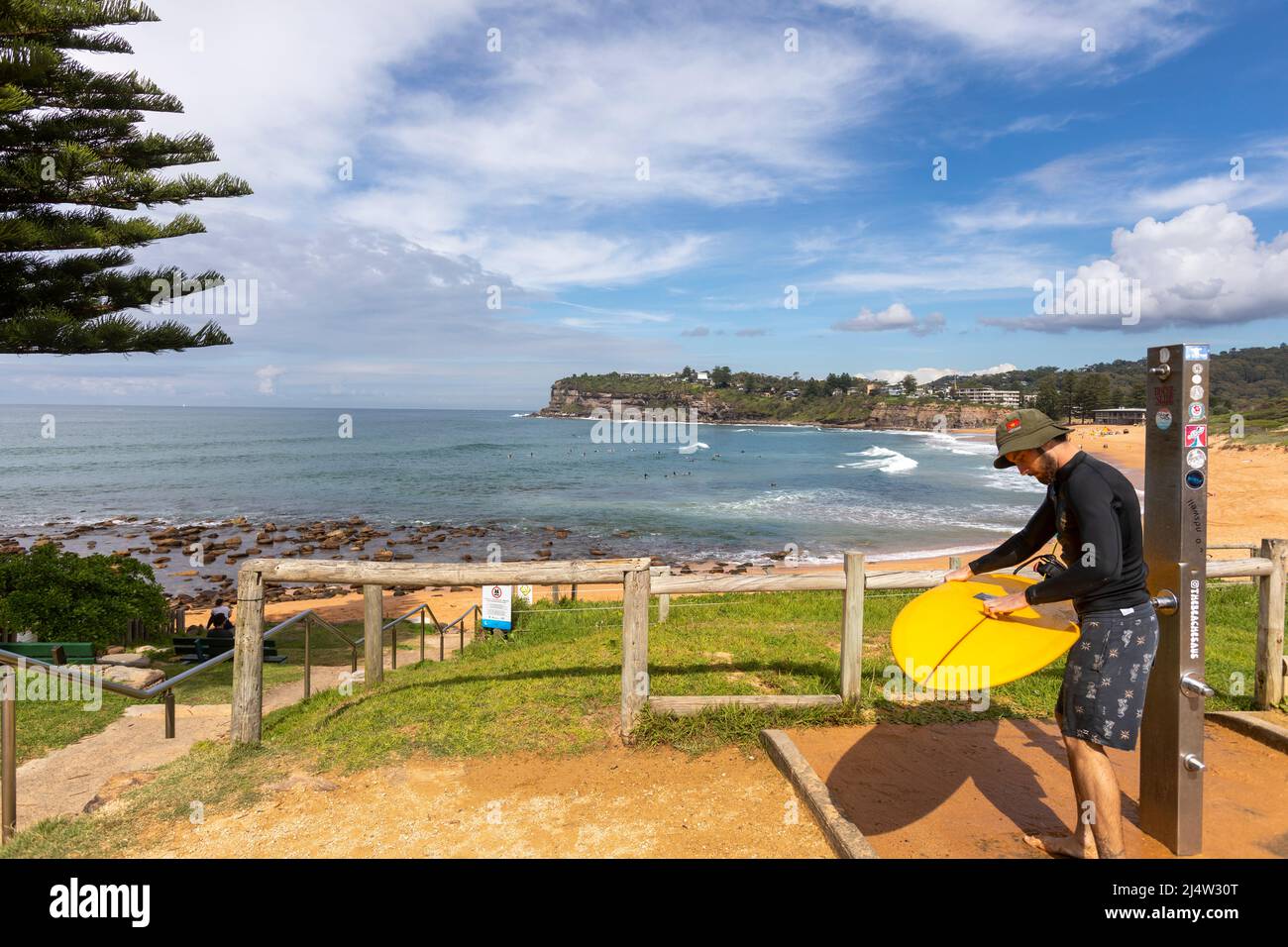 Surfer am Avalon Beach in Sydney beim Waschen des Surfbretts unter der Stranddusche, Sydney, NSW, Australien Stockfoto
