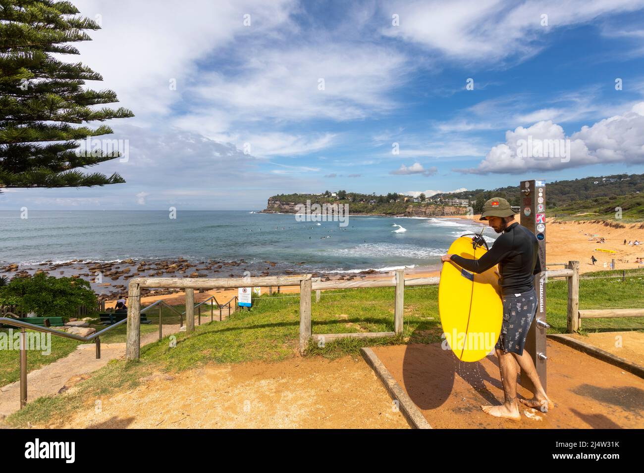 Surfer am Avalon Beach in Sydney beim Waschen des Surfbretts unter der Stranddusche, Sydney, NSW, Australien Stockfoto