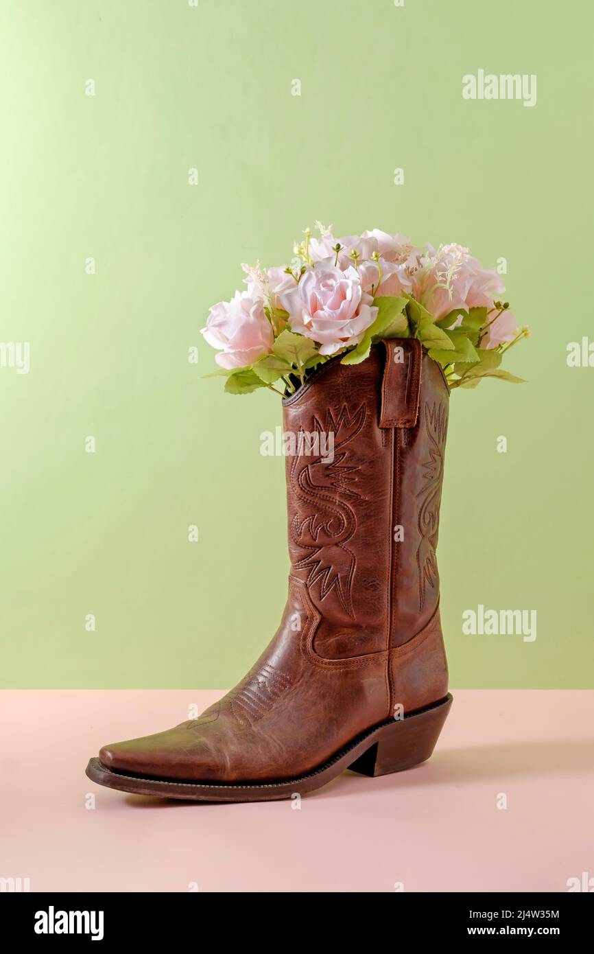 Cowboy Stiefel Schuhe und Blumenstrauß auf grünem Hintergrund minimal  kreatives Konzept Symbol des wilden westamerikas usa texas und Party  Stockfotografie - Alamy