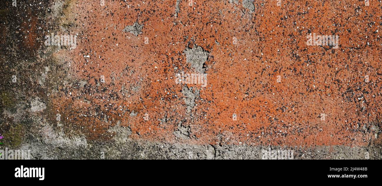 Alte Betonwand mit Rosttönen, grau, braun mit tiefen Spalten und Rissen. Hintergrundtextur. Speicherplatz Kopieren Stockfoto