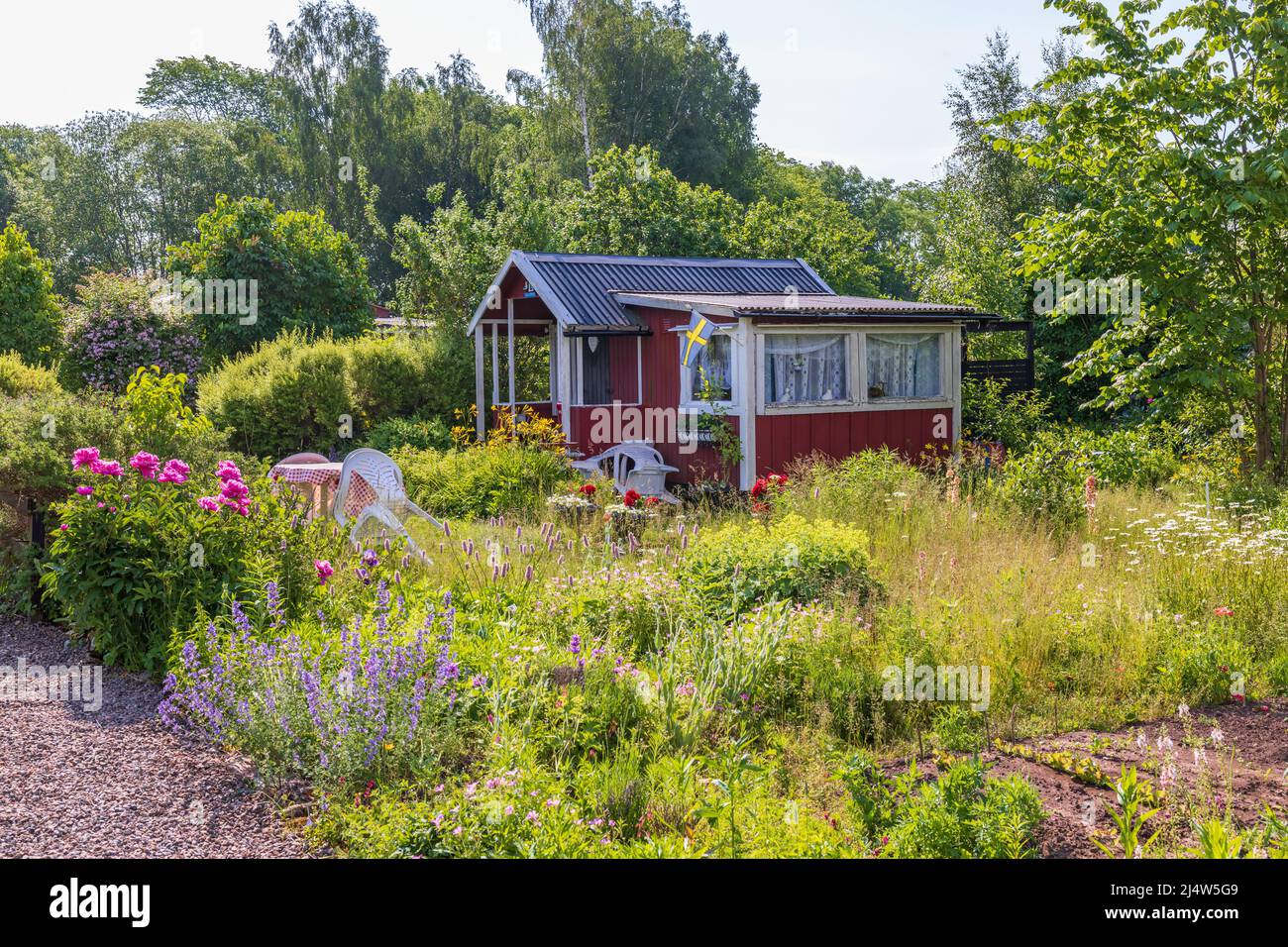 Idyllische rote Hütte in einem Schottgarten mit blühenden Blumen Stockfoto